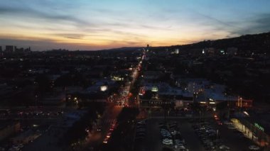 Akşamları kalabalık caddenin üzerinde ilerliyorlar. Romantik renkli günbatımı gökyüzü. Los Angeles, Kaliforniya, ABD