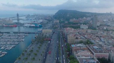 Kalabalık çok şeritli ana yolların havadan görüntüsü büyük şehirde rıhtıma çıkıyor. Marinada yelkenliler ve liman uzakta. Barselona, İspanya.
