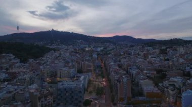Günbatımında şehir gelişiminin üzerinde ilerliyorlar. Tepelerin silueti ve arka planda kilise. Barselona, İspanya.