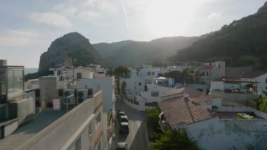Küçük sahil kasabasındaki evlerin oluşturduğu dar sokağın üzerinde ilerliyorlar. Batan güneşe karşı görüş. Garraf, İspanya.