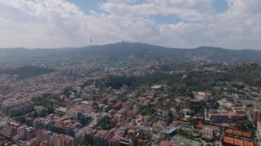Metropolis 'in üstünde uç. Tepedeki büyük şehrin havadan panoramik görüntüsü. Yüksek TV kulesinin silueti ve şehrin yukarısındaki tepede İsa 'nın Kutsal Kalbi Tapınağı. Barselona, İspanya.