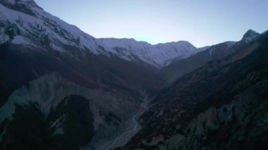 Vadideki iki dağ sırtının arasından akan nehrin havadan görüntüsü. Tepesinde kar olan güzel yüksek dağ manzarası. Manang Vadisi, Annapurna Gezisi, Nepal.