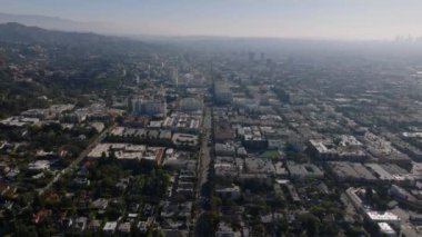 Metropolis 'teki binaların havadan panoramik görüntüsü. Geriye dönükse şehir merkezindeki evleri gösteriyor. Gün ışığına karşı puslu bir manzara. Los Angeles, Kaliforniya, ABD.
