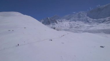 Himalayalar 'daki karlı dağlarda, arka planda karlı yürüyüş parkurunda yükselen bir grup yürüyüşçü. Annapurna gezisi. Manang. Nepal 'de. Asya.