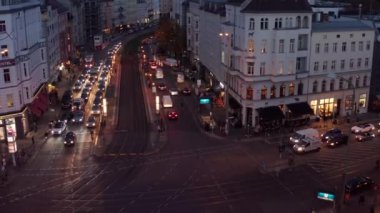 Şehir merkezindeki tramvay rayları ile kalabalık kavşaktan geçen çok şeritli caddedeki arabaların yüksek açılı görüntüsü. Berlin, Almanya.