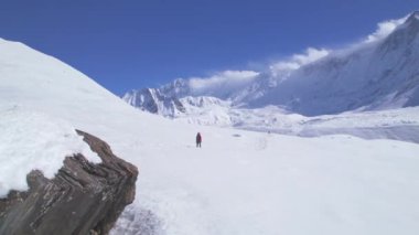 Hava görüntüsü, kırmızı ceketli erkek trekker 'ın Himalayalar' daki Tilicho Gölü kamp parkındaki tepeden aşağıya doğru yürüdüğünü gösteriyor. İlham verici gezgin maceraperest Asya 'yı tek başına keşfediyor.