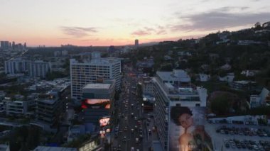 Günbatımında Metropolis 'teki işlek çoklu şeritli yolun üzerinde ilerliyorlar. Hollywood 'daki çok katlı binaların havadan görünüşü. Los Angeles, Kaliforniya, ABD