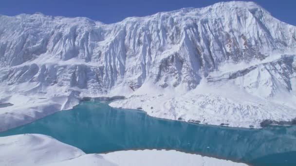 空中パンニング側のビュー水面に雪のヒマラヤ山の反射と青の高山ティリコ湖 ネパールだ マナンだ 地球上で最も高い高山湖の概念 — ストック動画