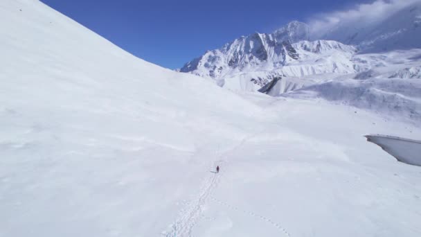空中后看男性徒步者在提利科湖小径雪地的小径上穿越高山湖 马南区Annapurna步行线路 探索尼泊尔喜马拉雅山 — 图库视频影像