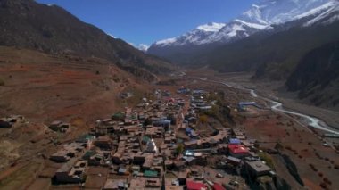 Himalayalar 'ın dağ sırasının arka planında Manang köyünün çatılarının üzerinde uçan bir hava aracı. Nepalli misafir evleri mimari ve toplum konsepti. Nepal 'de seyahat varış yeri
