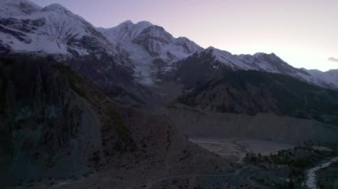 Himalayalar 'ın dağları, nehir vadileri üzerinde uçan hava sineması manzarası. Nepal 'in Manang bölgesinde. Yazın karlı tepelerin ardında gün batımı. Annapurna 'da gezinti gezisi
