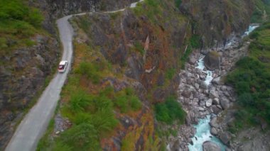 Himalayalar, Nepal 'deki dar dağ yolunda beyaz kamyonetin üzerinden uçarak geçiliyor. Macera tatili seyahatleri, Himalayalar 'da geziler.