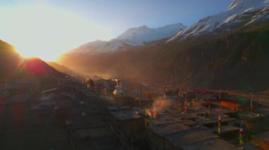 Yüksek irtifada uçan Manang köyü yerleşim yerlerinde güneş doğduğunda karlı Annapurna sıradağları doruklarıyla birlikte. Nepal 'de. Himalayalar dağ köyleri