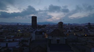 Gün batımında Metropolis 'in tarihi merkezindeki binaların üzerinde alçak uçuş. Gökyüzüne karşı eski kulenin silueti. Barselona, İspanya.