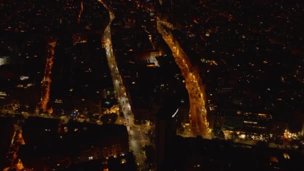 夜市内の街路灯や暗い建物によって照らされた通りの高い角度のビュー 交差点を通過車両 スペインのバルセロナ — ストック動画