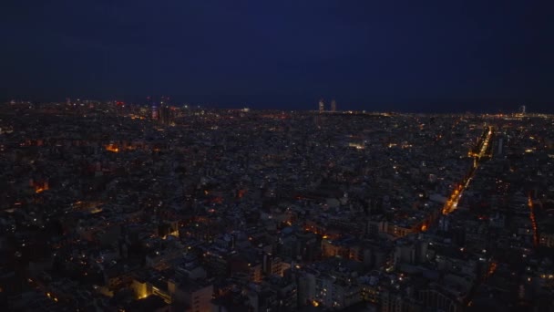 夕方には大都市の上を飛ぶ 街路灯が街を照らす夜の街のシーン スペインのバルセロナ — ストック動画