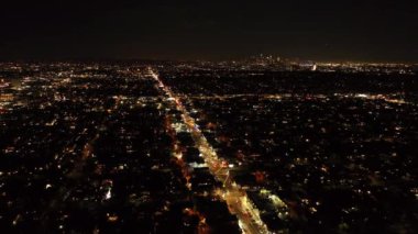 Gece şehrinin üzerinden geriye doğru uçuyor. Şehir merkezinde geniş bir bulvarda aydınlandı. Los Angeles, Kaliforniya, ABD