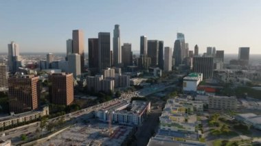 Altın saatinde şehir merkezinin üzerinden uç. Şehir merkezindeki gökdelenlerin gökyüzü manzarası. Los Angeles, Kaliforniya, ABD.