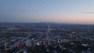 Metropolis 'in yukarısına uç. Alacakaranlıktaki büyük şehrin panoramik görüntüleri, uzun düz yolda giden arabalar. Los Angeles, Kaliforniya, ABD