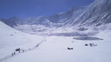 Minik alp gölü arka planına sahip ünlü Tilicho gölü yürüyüşü yapan bir grup yürüyüşçü. Nepal popüler yürüyüşleri. Himalayalar turları ve dağ yürüyüşü konsepti.