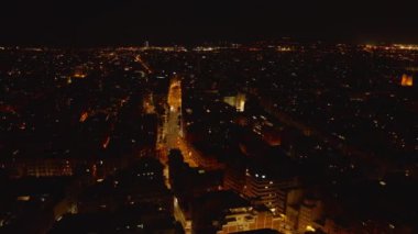 Gece şehrinin üzerinde uç. Karanlık binalarla çevrili aydınlık caddelerin hava manzarası. Barselona, İspanya.