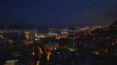 Akşamları şehir merkezindeki binaların üzerinden uçuyor. Gece parlayan tekneler ve limanlar. Barselona, İspanya.