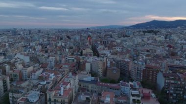 İleri, büyük şehrin üzerinden uçar. Günbatımından sonra şehir merkezindeki sokaklar ve çok katlı apartmanlar. Barselona, İspanya.