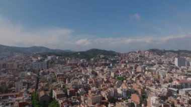 Kentsel çevredeki çok katlı binaların havadan panoramik görüntüsü. Arka planda ağaçlık tepeler var. Barselona, İspanya.