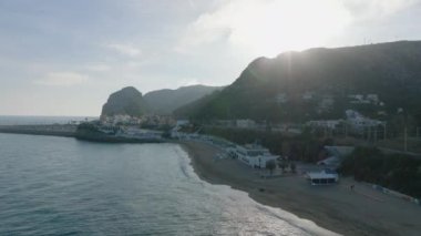 Deniz kıyısında uçmak. Kumlu sahil manzarası ve küçük sahil kasabasındaki binalar. Öğleden sonra deniz kenarında. Garraf, İspanya.