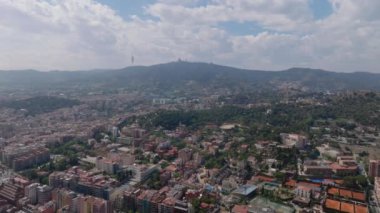 Metropolis 'in üstünde uç. Tepedeki büyük şehrin havadan panoramik görüntüsü. Yüksek TV kulesinin silueti ve şehrin yukarısındaki tepede İsa 'nın Kutsal Kalbi Tapınağı. Barselona, İspanya.