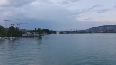 İleri su yüzeyinin üzerinden uçar. Rıhtım boyunca restoran tekneleri. Gün batımından sonra sakin. Zürih, İsviçre.