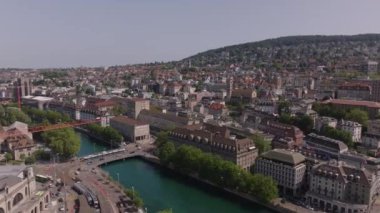 Şehirdeki nehirde işlek taşıma caddelerinin üzerinde ilerliyorlar. Şehir merkezindeki binalar. Zürih, İsviçre.