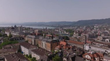 Şehir merkezindeki binaların üzerinden uçuyor. Şehrin ve gölün havadan panoramik görüntüsü. Zürih, İsviçre.
