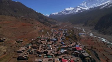 Himalayalar 'ın dağ sırasının arka planında Manang köyünün çatılarının üzerinde uçan bir hava aracı. Nepalli misafir evleri mimari ve toplum konsepti. Nepal 'de seyahat varış yeri