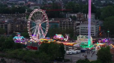 Şehirdeki eğlence parkında neon renkli havanın parlaklığı. Uzun kule ve dönme dolap. Zürih, İsviçre.