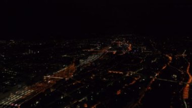 Geceleri şehrin havadan panoramik görüntüsü. Aydınlatılmış sokaklar ve demiryolu altyapısı kararmış binalarla birleşiyor. Zürih, İsviçre.