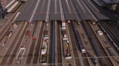 Ana tren istasyonundaki platformların yüksek açılı görüntüsü. Raylarda trafik, çeşitli kalkış ve varış trenleri. Yukarı kaldır ve şehir manzarasını göster. Zürih, İsviçre.