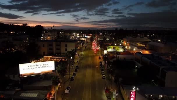 前方のライトアップされた通りの上を夕方の街を飛ぶ 都市のバラで車の運転 米国カリフォルニア州ロサンゼルス — ストック動画