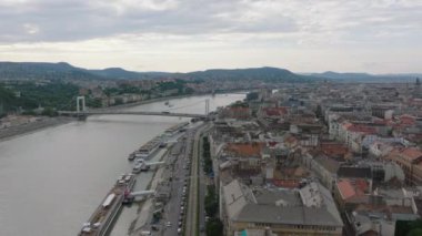 Hava manzaralı binalar ve rıhtımdaki işlek yol. Tuna nehri boyunca uzanan asma köprü. Bulutlu bir günde şehir manzarası. Budapeşte, Macaristan.