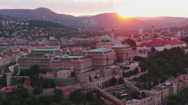 美丽浪漫的布达城堡的空中镜头与日落相对照 靠近河流的山丘和背景的山丘上的历史建筑群 匈牙利布达佩斯 — 图库视频影像