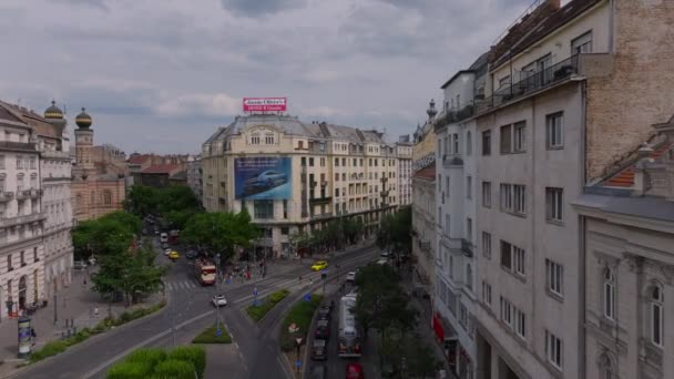 その後 市内中心部の通りとクロスロードを越えて飛ぶ ディスコ ストリート シナゴーグ近くの歴史的な多国籍建築物 壁のビルボード広告 ブダペスト ハンガリー — ストック動画