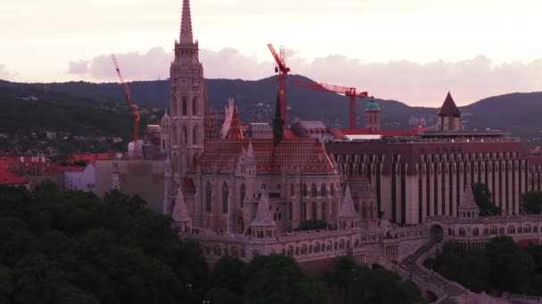 渔夫城堡和马蒂亚斯教堂在日落的天空中高耸的滑梯和平底锅镜头 塔式起重机位于建筑工地 匈牙利布达佩斯 — 图库视频影像