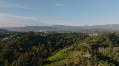 Banliyölerdeki doğa manzarası, parktaki ağaçlar ve arka plandaki dağlar. Los Angeles, Kaliforniya, ABD.
