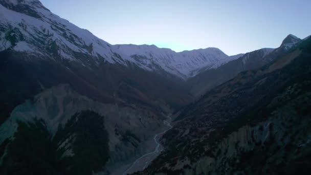 2つの山の尾根の間の谷に流れる川の空中撮影 上に雪が降る美しい山の風景 マナンバレー アンナプルサーキットトレック ネパール — ストック動画