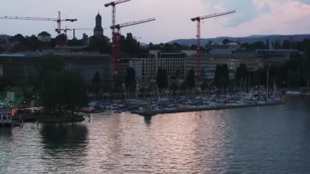 塔式起重机的轮廓群对着天空 黄昏的时候 湖滨有码头和城市里的建筑物 瑞士苏黎世 — 图库视频影像