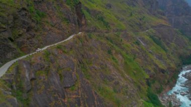 Yukarıdan aşağıya 4wd araç dar ve tehlikeli çakıllı yolda ilerliyor. Himalayalar 'da yolculuk macerası. Annapurna devresi. Manang kavramının resimli yolu 