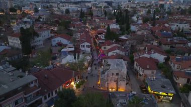 Şehir merkezinin dar sokaklarında yürüyen insanların yüksek açılı görüntüsü. Alacakaranlıktaki tarihi kasaba bölgesi. Antalya, Türkiye.