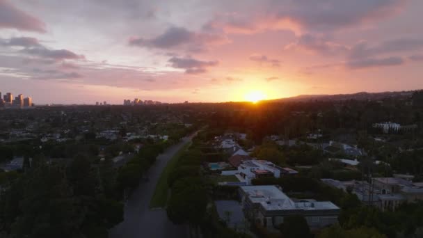 前方マルチレーン道路の都市郊外につながる上に飛ぶ カラフルな夕日に対する空中の景色 米国カリフォルニア州ロサンゼルス — ストック動画