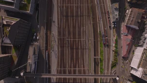 複数の線路とスイッチを備えた広い鉄道の庭に移動する列車のトップのパンニング映像 緑の屋根と植生のある周辺の建物 チューリッヒ スイス — ストック動画