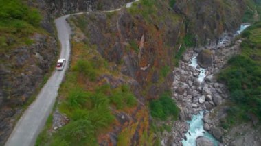Himalayalar, Nepal 'deki dar dağ yolunda beyaz kamyonetin üzerinden uçarak geçiliyor. Macera tatili seyahatleri, Himalayalar 'da geziler.